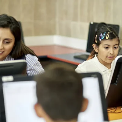 Profesora acompaña a estudiantes en una sala de computación en Chile.