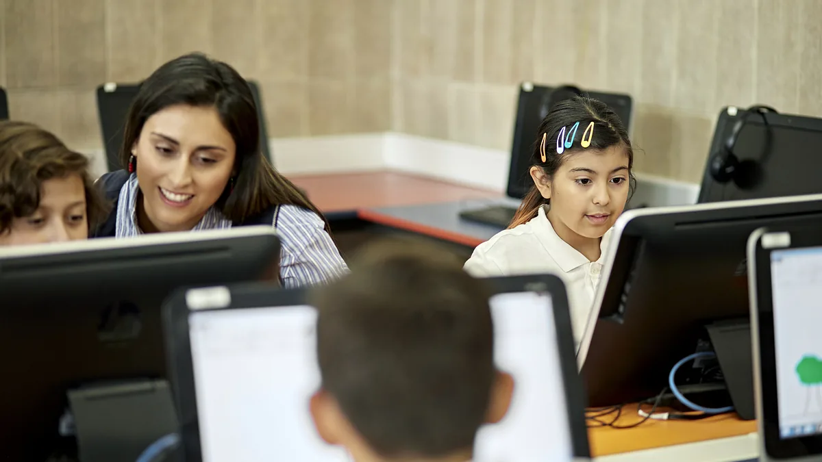 Profesora acompaña a estudiantes en una sala de computación en Chile.